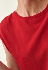 Rotes Kurzarmoberteil mit rundem Halsausschnitt und glattem, strukturiertem Stoff. Es sind keine Muster oder zusätzlichen Akzente sichtbar.