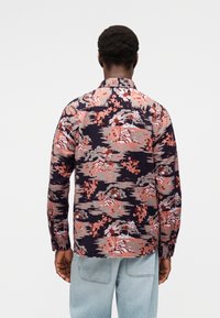 Πουκάμισο με μακριά μανίκια και μοτίβο με λουλούδια και τοπία σε αποχρώσεις του ναυτικού μπλε, κοραλί και γκρι. Κατασκευασμένο από ελαφρύ ύφασμα με άνετη εφαρμογή.