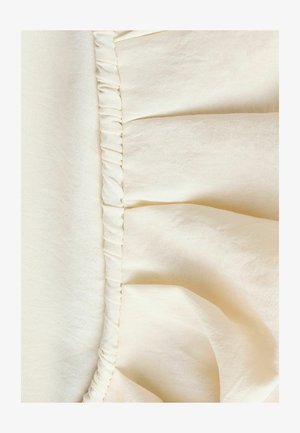 Tejido de color beige claro con una costura fruncida y puntadas finas, que muestra una textura suave y un sutil brillo.