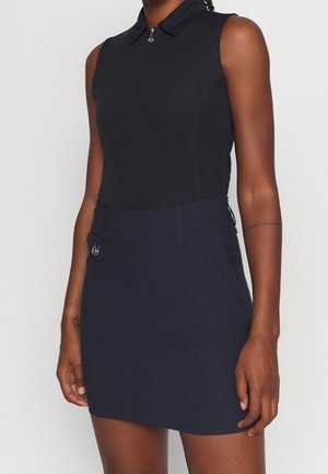 Top negro sin mangas con cuello y cremallera frontal, combinado con una falda azul marino de talle alto que presenta un pequeño detalle de cremallera plateada.