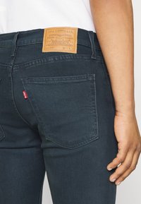 Mörka denimjeans har en läderlapp med märkning, bakfickor med distinkt sömnad och en slim fit-design.