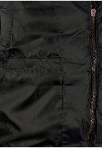 Schwarze Pufferjacke mit glatter Textur, einem Reißverschluss mit bronzefarbenen Details und einer Brusttasche auf der linken Seite.