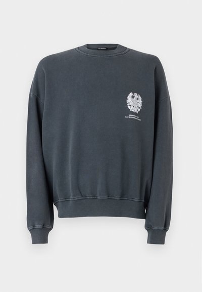Sweatshirt cinza escuro com punhos e bainha canelados. Apresenta um design gráfico branco na área do peito esquerdo e um decote tipo crew clássico.