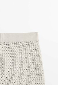 Light gray knitted fabric featuring a textured, open pattern with a smooth, elastic waistband. No visible hardware or accents.