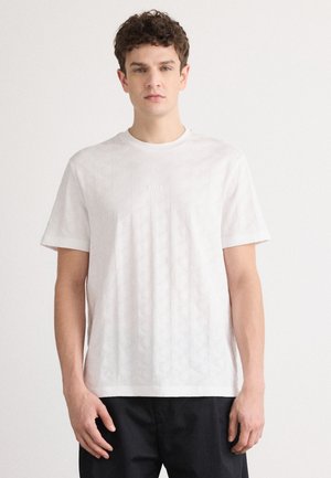Tricou alb cu mânecă scurtă, având un model geometric texturat. Este prevăzut cu guler rotund și o marcă subtilă în centrul său.