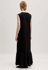 Schwarzes ärmelloses Maxikleid mit Rundhalsausschnitt und Rüschensaum, aus weichem Stoff gefertigt. Glatte Textur und keine sichtbaren Muster oder Beschläge.