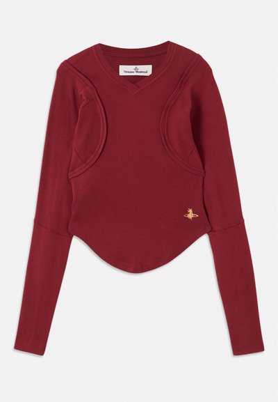 Rød langermet topp med V-hals og unike skuldersnitt. Ribbete tekstur og buet kant. Liten gulllogo på siden.