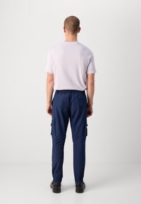 Marine cargo bukser med elastisk livlinje, sidelommer og gathered cuffs, paret med en lys grå t-skjorte med korte ermer.