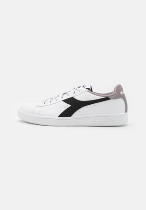 Sneaker bianco con accenti neri e grigi, materiale in pelle liscia, punta rotonda, suola piatta e sistema di lacci. Logo sul lato e sul tallone.