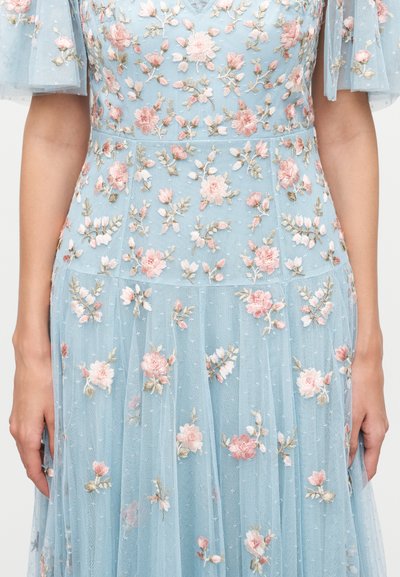Lyseblå kjole med gennemsigtigt stof og pink blomsterbroderi, med korte ærmer og en flydende nederdel.