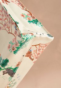 Vászontáska virág- és állatminta mintákkal pasztell színekben, zöld, rózsaszín és barna részletekkel. Strukturált alakzat varrott szegélyekkel.