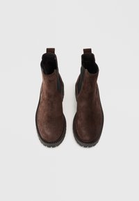 Botas de tobillo de ante marrón con paneles laterales elásticos negros y suelas de goma texturizadas, que cuentan con una lengüeta en la parte trasera para facilitar el uso.