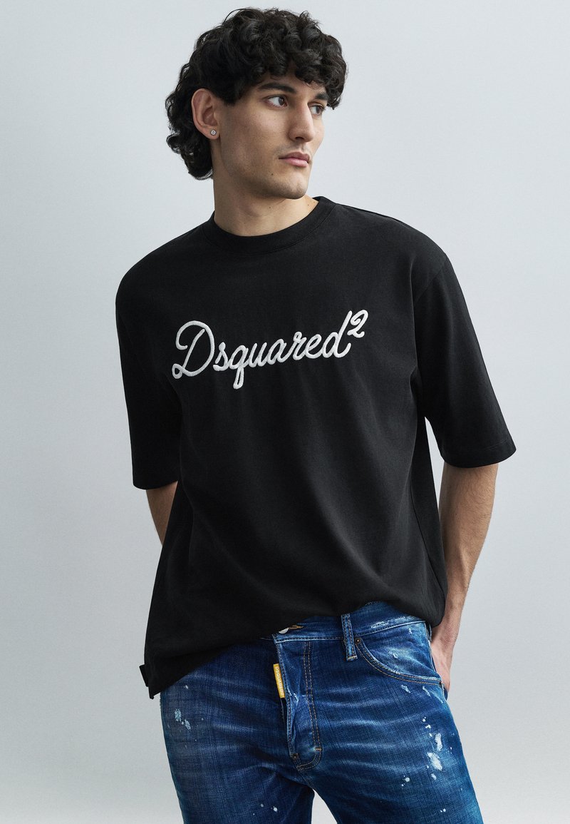 Black short-sleeve t-shirt featuring white embroidered "Dsquared²" logo on the front. The fabric appears smooth, with a relaxed fit.