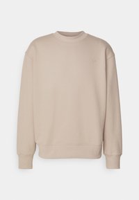 Beige sweatshirt i mjukt tyg, med rund hals, långa ärmar och en liten broderad logotyp på bröstet. Minimalistisk design.