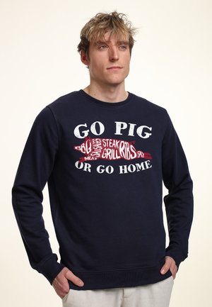 Mørkeblå sweatshirt i bomuld med et stort grafisk design i rød og hvid tekst: "GO PIG OR GO HOME" med madrelaterede former.