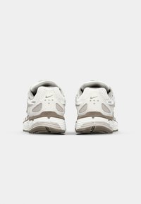 Weiße und hellgraue Sportschuhe aus Mesh- und Synthetikmaterialien, mit abgerundeter Spitze, gepolstertem Schaft und strukturiertem Zwischensohlenbereich.
