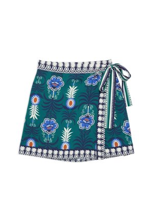 Jupe portefeuille bleu sarcelle avec des motifs floraux et d'ananas bleus et blancs, bordée d'une bande géométrique marine et blanche, nouée sur le côté avec un nœud rayé.