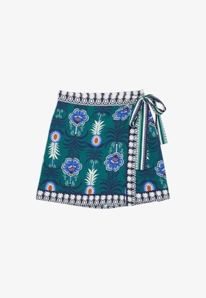 Jupe portefeuille bleu sarcelle avec des motifs floraux et d'ananas bleus et blancs, bordée d'une bande géométrique marine et blanche, nouée sur le côté avec un nœud rayé.