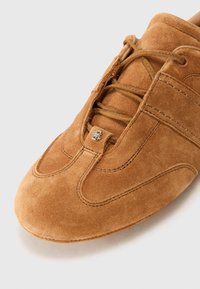 Adidași maro din suede cu cusături tonale, vârf rotunjit și design cu șireturi. Prezintă un mic logo metalic în partea superioară.