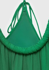 Haut de bikini triangulaire en tissu vert avec de fines bretelles ajustables et une bande élastique froncée le long du bord inférieur.