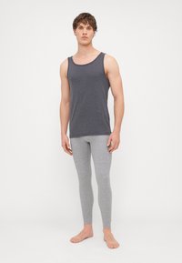 Szürke pamut pántnélküli felső és világosszürke leggings, testhezálló dizájn, puha textúra, lapos varrások, minimalista stílus, mezítláb, sima háttér.