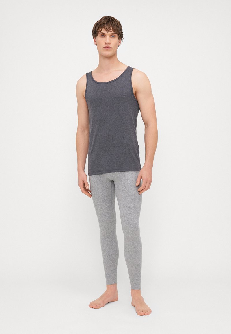 Szürke pamut pántnélküli felső és világosszürke leggings, testhezálló dizájn, puha textúra, lapos varrások, minimalista stílus, mezítláb, sima háttér.