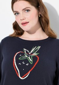 Marineblau gestrickter Pullover mit Erdbeerdesign, ausgestattet mit lebhaften roten, grünen und weißen Akzenten. Runder Ausschnitt, weiche Textur.