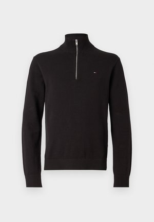 Maglione nero in tessuto a maglia, con colletto alto e chiusura a mezza zip. Polsini e orlo a costine, con un piccolo logo sul petto.