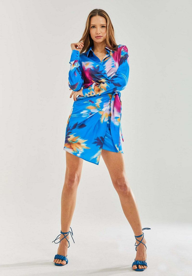 Wrap dress in vibrant blue with pink and orange floral patterns. Long sleeves, collared neckline, side tie, asymmetric hem. Smooth fabric.