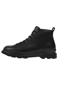 Las botas de cuero negro hasta el tobillo cuentan con una punta redondeada, un diseño con cordones y una suela de goma texturizada con un agarre sustancial.