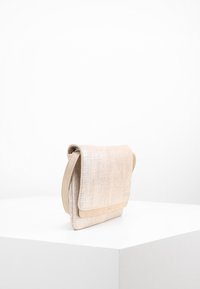 Bolso de hombro metálico beige con superficie texturizada, cierre de solapa y panel lateral liso; forma rectangular con un diseño sencillo.