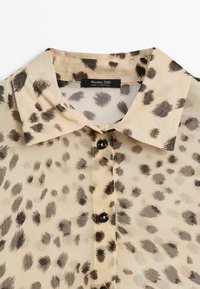 Beige button-up shirt with black and gray leopard print pattern and a pointed collar, labeled Massimo Dutti, made in Portugal.
