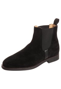 Bottine en daim noir avec panneaux latéraux élastiques, languette à l'arrière et semelle en cuir lisse. Design minimaliste sans élément métallique apparent.