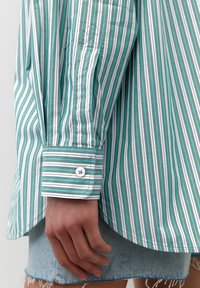Camicia con bottoni a righe verdi e bianche, in tessuto leggero, maniche lunghe con polsini con bottoni, caratterizzata da un piccolo dettaglio a diamante ricamato.