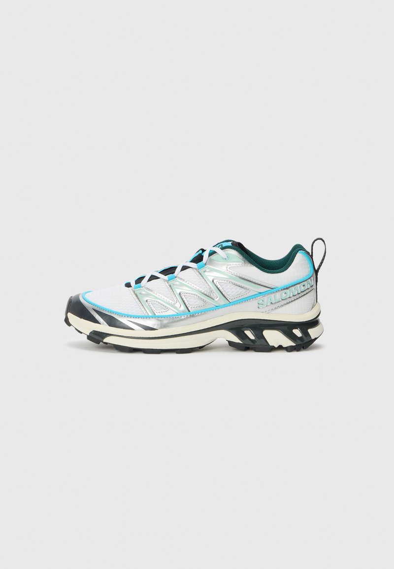 Chaussure de trail légère avec un dessus en argent métallique, des accents turquoise, une semelle noire, et un maillage texturé pour la respirabilité.