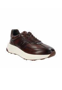 Donkerbruin leren sneaker met dikke witte zool, bruine veters en subtiele zwarte logo aan de zijkant, schuin gepositioneerd om de buitenzijde en de teen te tonen.