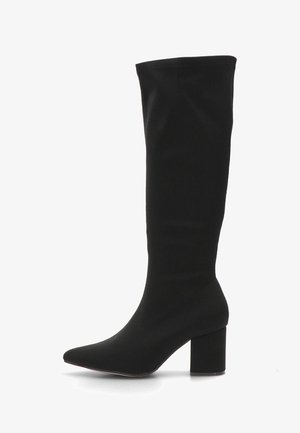 Bota negra hasta la rodilla hecha de material elástico, con punta afilada y tacón cuadrado. Textura suave sin herrajes visibles.