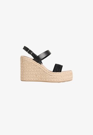 Sandale compensée à plateforme tissée beige avec bride de cheville en cuir noir et bride d'orteil en tissu noir ornée d'un logo embossé.