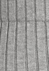 Grå stickad tyg med vertikal ribbad struktur och alternerande släta band. Mjukt, lättviktigt och flexibelt material.