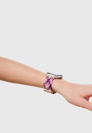 Håndled med et smartwatch med et vævet stofbånd i lilla, pink og hvid chevronmønster på en lysegrå baggrund.