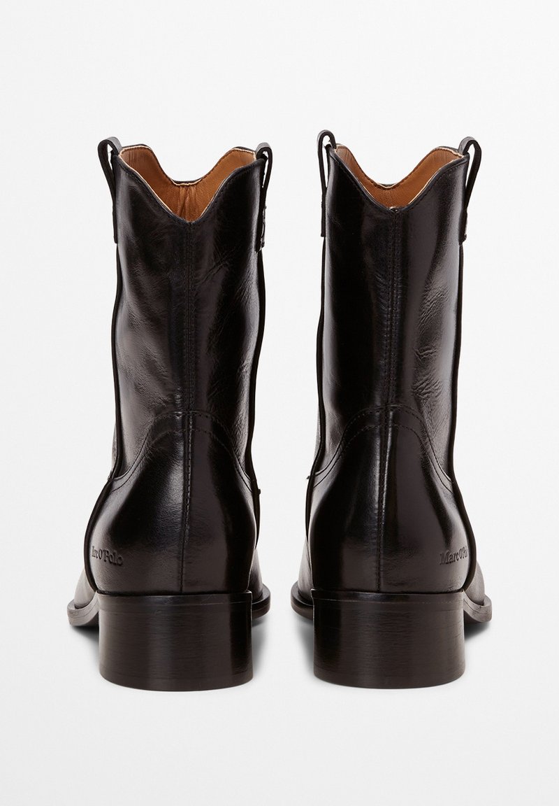Czarne skórzane botki za kostkę o gładkiej fakturze, z ostro zakończonym noskiem i średnim obcasem w kształcie bloku. Posiadają wypukłe szwy i uchwyty do zakładania na górze.