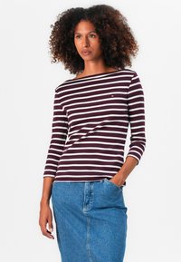 Bordeauxrot und weiße gestreifte langärmlige Bluse mit einem Bootsausschnitt. Kombiniert mit einem blauen Denimrock mit Vorderentaschen.