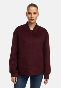 Bordeaux fleece jack met een ronde kraag, knopen sluiten en zijzakken. Kenmerkt zich door een losse pasvorm en geribde manchetten voor comfort.
