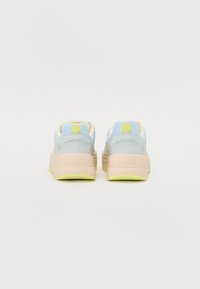 Sneakers with a light blue mesh upper, gray accents, cream details, and a cushioned beige sole. Features a circular logo on the heel.