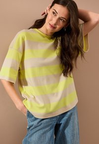 Tričko s krátkym rukávom a voľným strihom v béžovej a jasne žltej horizontálnej pruhovanej vzorke, s okrúhlym výstrihom a neformálnym dizajnom.