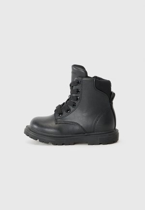 Bota de tobillo de cuero negro con cordones, cuello acolchado y suela de goma texturizada. Presenta acentos de costura y un logo grabado en la lengüeta.