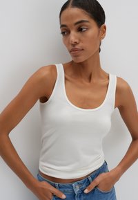 Witte katoenen tanktop met brede banden, een ronde halslijn en een aansluitend ontwerp. Gecombineerd met blauwe denim jeans voor een casual look.
