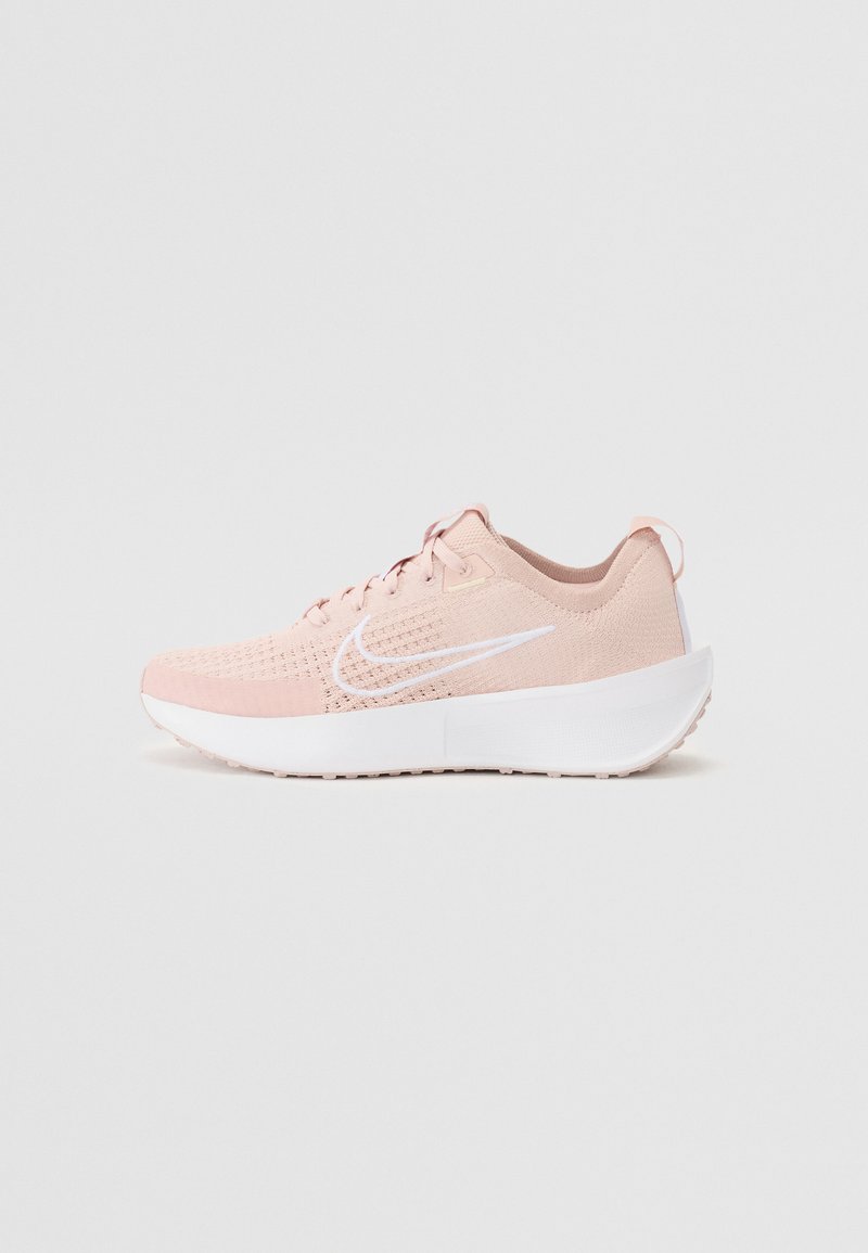 Helle rosa Sportschuh mit einem atmungsaktiven Mesh-Obermaterial, weißem Nike-Swoosh und einer dicken weißen Sohle. Verfügt über strukturierte Nähte und Schnürsenkel.