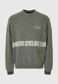 Pelēks vilnas džemperis ar apaļu kaklu, uz kura ir balts uzraksts "ANMARR CYCLING CLUB", zaļi un bordo svītraini aproces un izšuvumu detaļas.