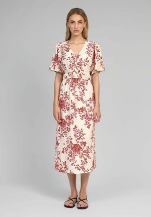 Robe midi florale beige clair avec des motifs floraux rouges et roses. Elle présente des manches courtes bouffantes et une taille élastique pour un look ajusté.